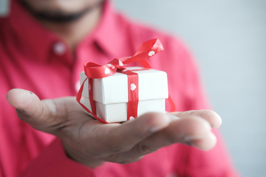 Man holding a small gift box with a red ribbon